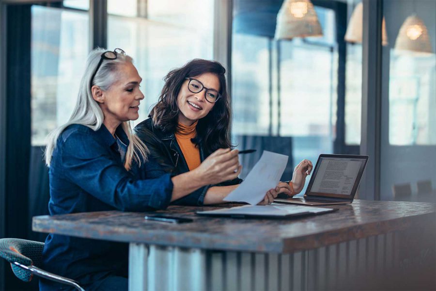 Two women sat at a table looking at a report